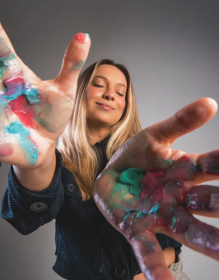 Retrato artístico feminino com mãos sujas de tinta colorida